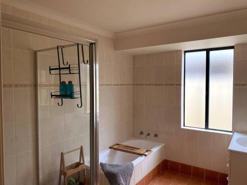 a bathroom with a shower and a tub and a window at The Sundowner in Esperance
