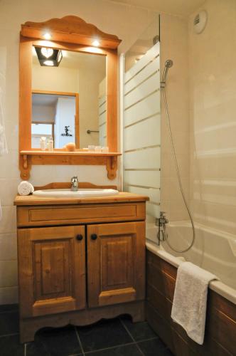 une salle de bain avec un lavabo, un miroir et une baignoire dans l'établissement Lagrange Vacances Les Hauts de Comborcière, à La Toussuire