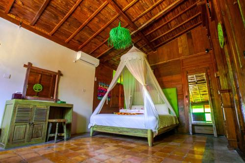 a bedroom with a bed with a canopy in a room at Salim Beach Resort in Gili Air