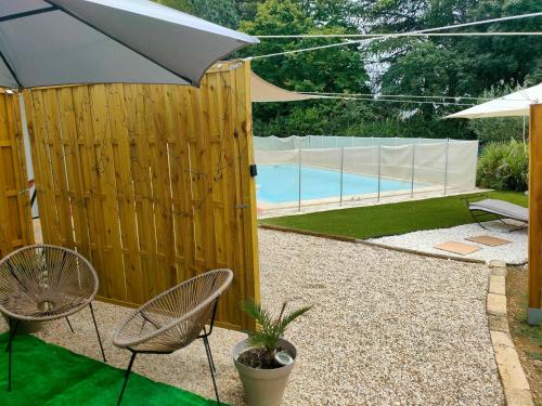 a wooden fence with two chairs and an umbrella at Au Mazet du Parc in Lédenon