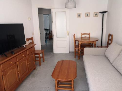 ein Wohnzimmer mit einem Sofa, einem TV und einem Tisch in der Unterkunft Apartamento Aretusa Luz in Zahara de los Atunes