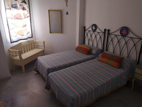 1 Schlafzimmer mit 2 Betten, einem Stuhl und einem Spiegel in der Unterkunft Apartamento Aretusa Luz in Zahara de los Atunes