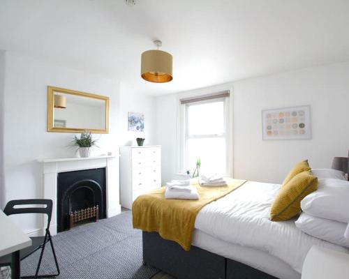 a white bedroom with a bed and a fireplace at City Centre 4 Bedroom House in Winchester