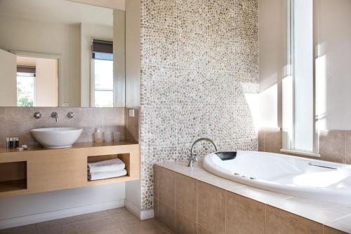 a bathroom with a tub and a sink and a mirror at Orford Panache in Daylesford