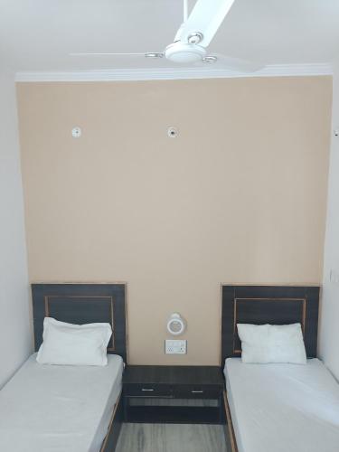 two beds in a room with white walls at Aarambh Residency in Khajurāho
