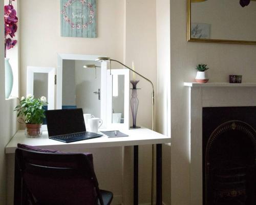 a desk with a laptop computer on top of a fireplace at City Centre 4 Bedroom-Sleeps 8! in Winchester