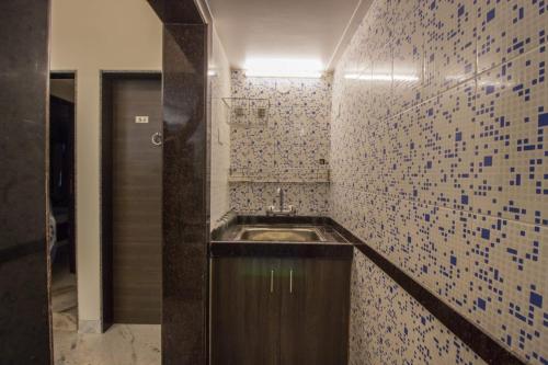 La salle de bains est pourvue d'un lavabo et d'un mur carrelé. dans l'établissement Calangute Beach Way, à Calangute