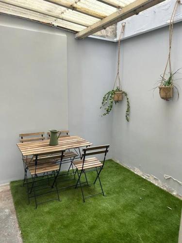 un patio con mesa y sillas con césped verde en Le petit Championnet T2 en Grenoble