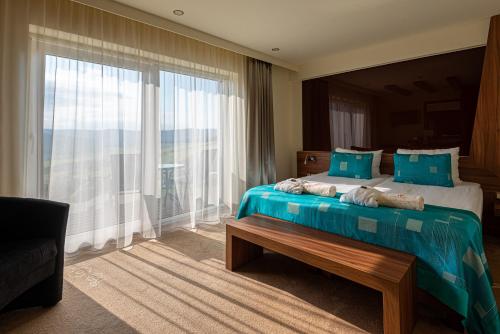 a hotel room with a bed and a large window at Castellum Hotel Hollókő in Hollókő