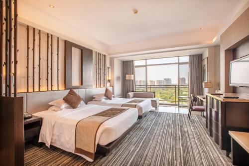a hotel room with two beds and a television at Mission Hills Resort Haikou in Haikou