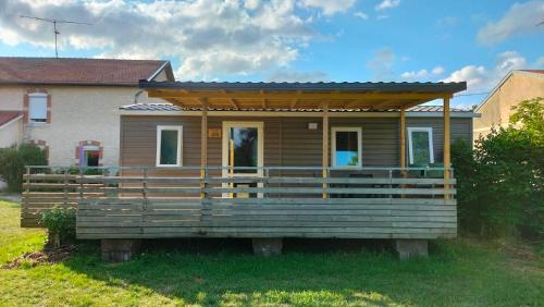 a tiny house with a porch in a yard at Cottage gîte aux Lauriers Lacroix sur meuse in Lacroix-sur-Meuse