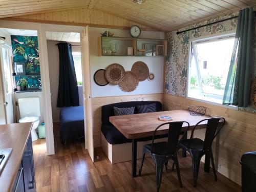 a tiny house with a wooden table and chairs at Cottage gîte aux Lauriers Lacroix sur meuse in Lacroix-sur-Meuse