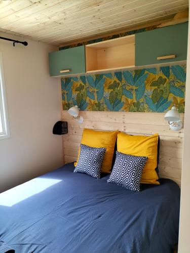 - une chambre avec un lit doté d'oreillers jaunes et bleus dans l'établissement Cottage gîte aux Lauriers Lacroix sur meuse, à Lacroix-sur-Meuse