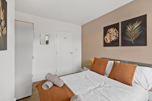 a bedroom with a bed with white sheets and orange pillows at Stylish Great Location Near Tamar Bridge in Saltash