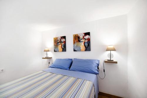 a bedroom with a bed and three paintings on the wall at Obispo Rancés in Chiclana de la Frontera