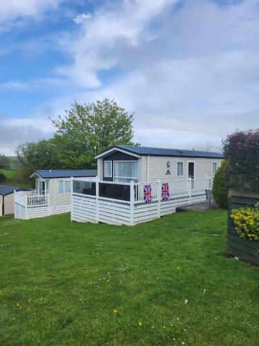 a white caravan with a fence and a yard at Wood Farm Holiday Park in Charmouth