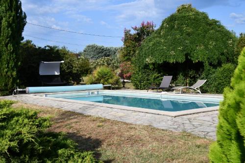 a swimming pool in a garden with two lawn chairs at Mas La belle Ambroise - Chambres d'hôtes et Gîte in Saint-Ambroix