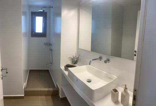 a white bathroom with a sink and a mirror at Levanda Guest Houses in Andiparos