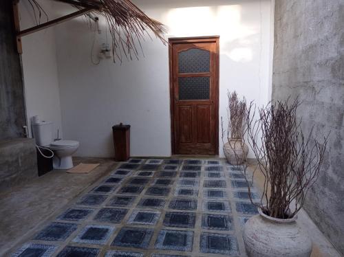 a bathroom with a toilet and a wooden door at CocoVilla Boutique Resort in Beruwala