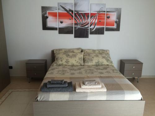 ein Schlafzimmer mit einem Bett mit zwei Tischen und einem Wandgemälde in der Unterkunft B&B Camelie in Melfi