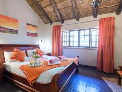 a bedroom with a large bed with orange curtains at Motozi Lodge in Pelindaba