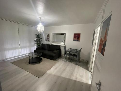 a living room with a black couch and a table at NEW! Xtra Large 4 bedroom Up to 12 guests in Woolwich