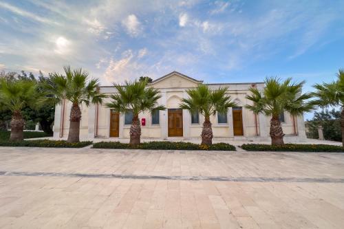 a building with palm trees in front of it at Borgo Vita Novella Resort in Marzamemi