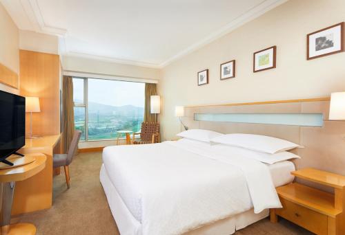 um quarto de hotel com uma grande cama branca e uma televisão em Four Points by Sheraton Shenzhen em Shenzhen