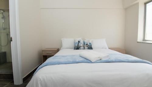 a bedroom with a large white bed with blue sheets at 21 Bronze Bay Umhlanga Rocks in Durban