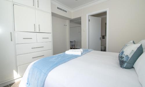 a white bedroom with a large bed and white cabinets at 21 Bronze Bay Umhlanga Rocks in Durban