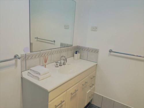 La salle de bains blanche est pourvue d'un lavabo et d'un miroir. dans l'établissement Thistledome, à Esperance