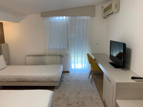 a room with two beds and a desk with a television at Royal L Hotel in Carev Dvor