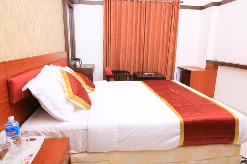 a hotel room with a large bed and a desk at Amala's Residency in Trivandrum