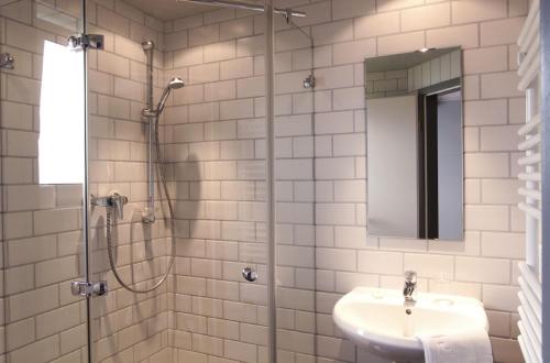 a bathroom with a shower and a sink and a mirror at Hotel-amSee in Allensbach