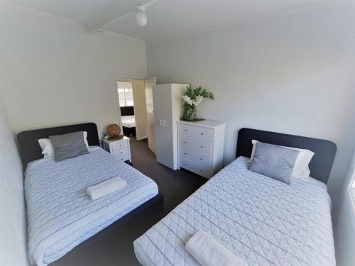 エスペランスにあるThree Palms Apartments Unit 1のベッドルーム1室(白いシーツとドレッサー付きのベッド2台付)