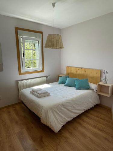 1 dormitorio con 1 cama blanca grande con almohadas azules en A Casiña, en Monforte de Lemos