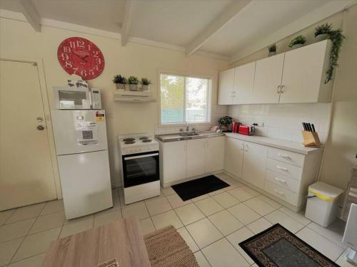a kitchen with white appliances and a red clock on the wall at Esperance Little Units 2 in Esperance