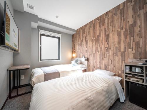 um quarto com 2 camas e uma parede de madeira em Super Hotel Premier Namba Shinsaibashi Natural Hot Spring em Osaka