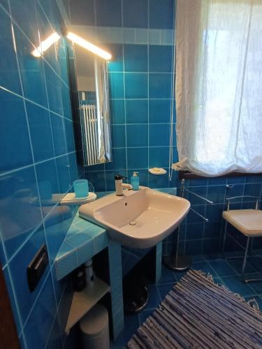 a blue tiled bathroom with a sink and a mirror at Camera nella Casa dei Tigli in Treviso