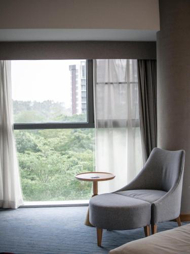 a room with a chair and a table in front of a window at Aloft Dongguan Songshan Lake in Dongguan