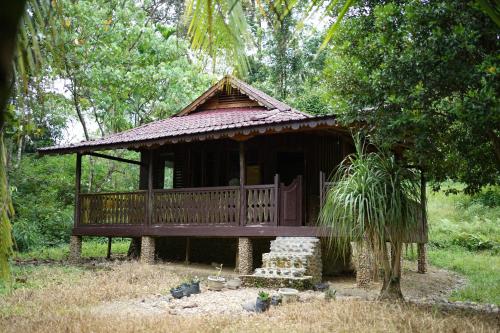 a small hut with a deck in a forest at Batu Kapal Lodge in Bukit Lawang
