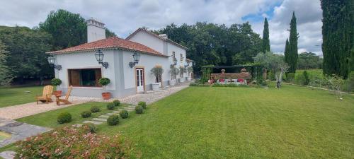 a small white house with a yard with a grass yard at Quinta dos Pegões in Tomar