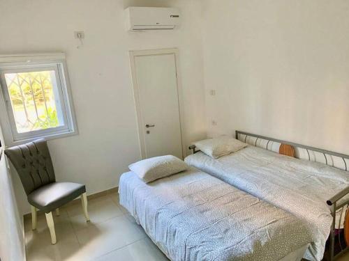 a bedroom with two beds and a chair and a window at Family House in Natanya in Netanya