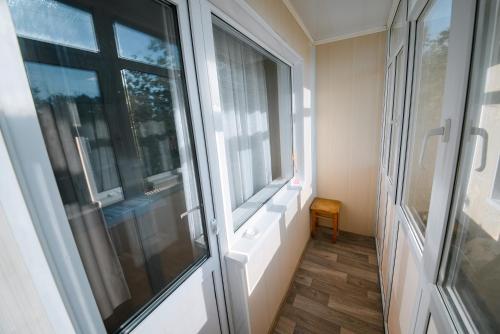 um quarto com 2 janelas e um piso de madeira em Металлургов 10 em Temirtaū