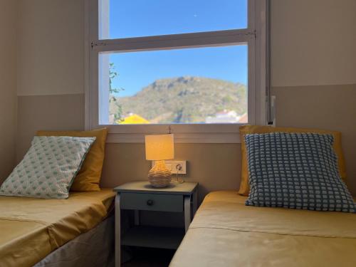two beds in a room with a window and a table at Calma Marína Roses in Roses
