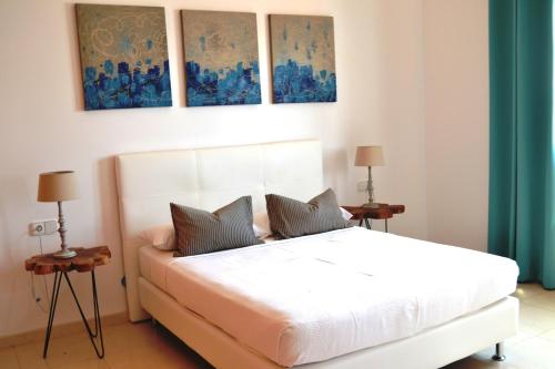 1 dormitorio con 1 cama blanca y 3 pinturas en la pared en Grand Villa Famara Los Mojones by Dolores, en Puerto del Carmen