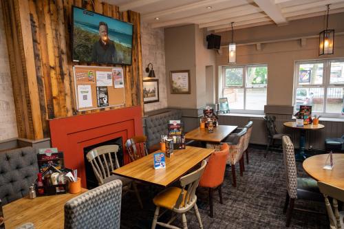 a restaurant with tables and chairs and a fireplace at Old Grey Mare Inn by Greene King Inns in Hull