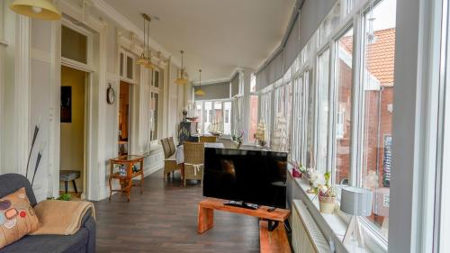 uma sala de estar com uma televisão, um sofá e janelas em Ferienwohnung Bubikat em Borkum