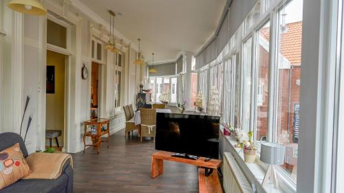 a living room with a tv and a couch and windows at Ferienwohnung Bubikat in Borkum