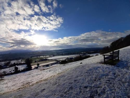 a bench sitting on top of a snow covered hill at Coddiwomple in Leyburn